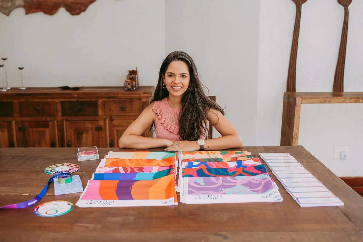 Designer sorrindo com amostras coloridas de tecido, simbolizando criatividade e expressão artística