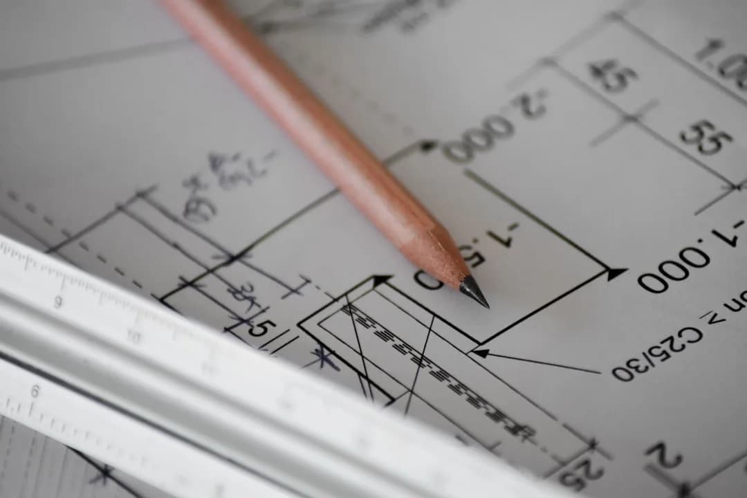 Planta técnica de engenharia com cotas, lápis e régua, simbolizando trabalho prático e projetual