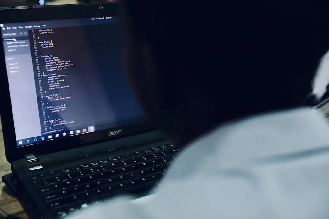 Profissional de tecnologia trabalhando em laptop com código na tela