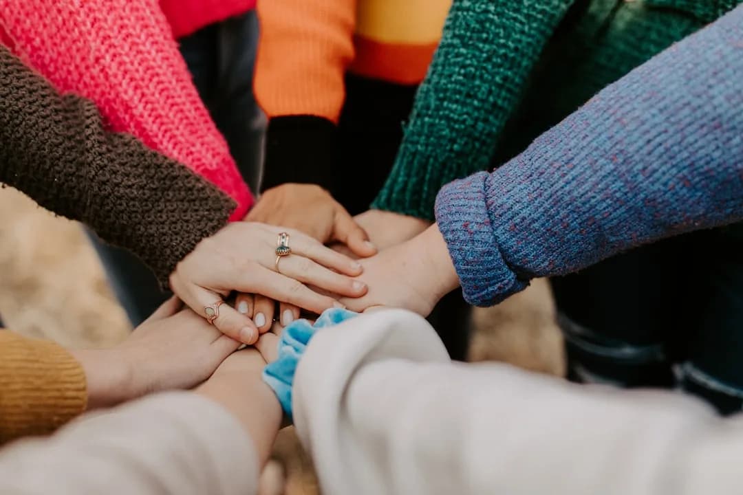 Equipe com as mãos unidas representando colaboração, estabilidade e harmonia profissional